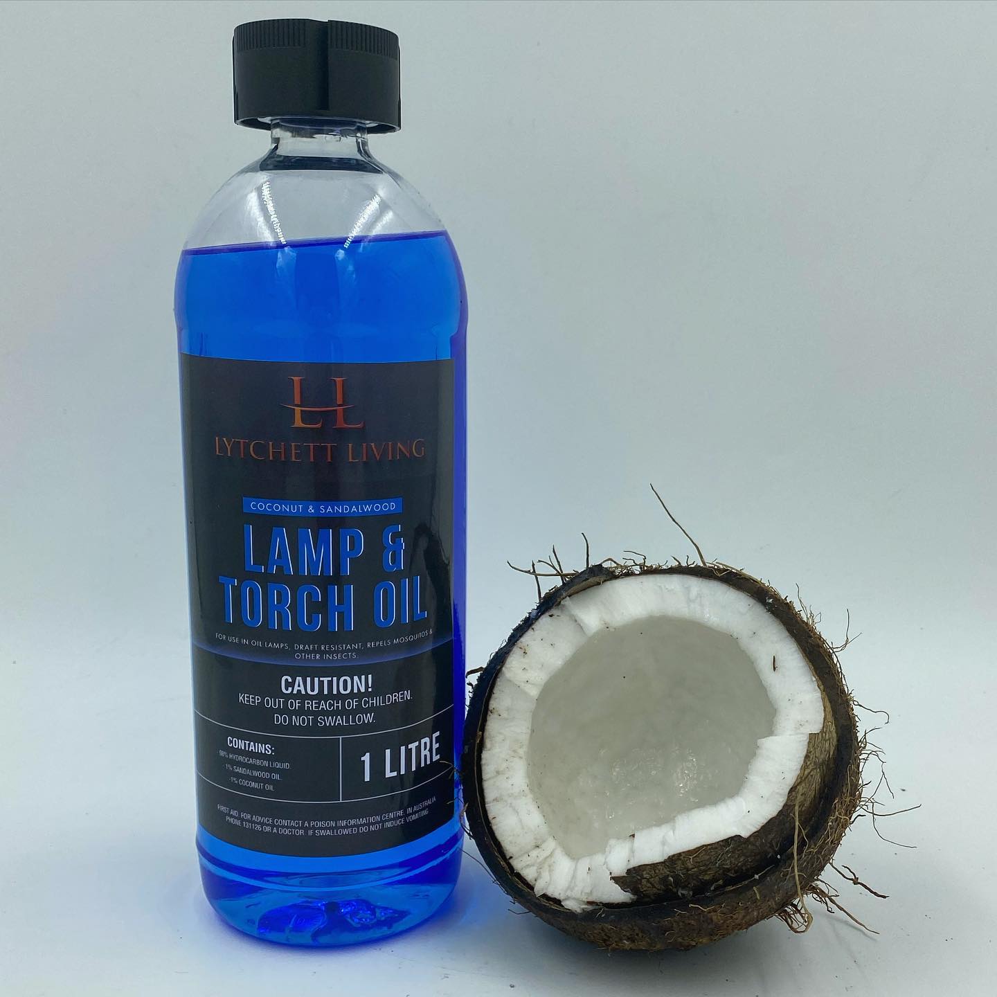 Blue bottle of sandalwood/coconut oil pictured beside half of a coconut